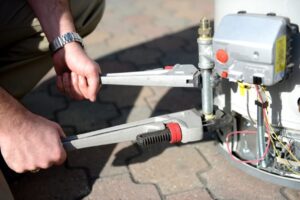 A close-up of a plumber from Mike Counsil Plumbing repairing a water heater